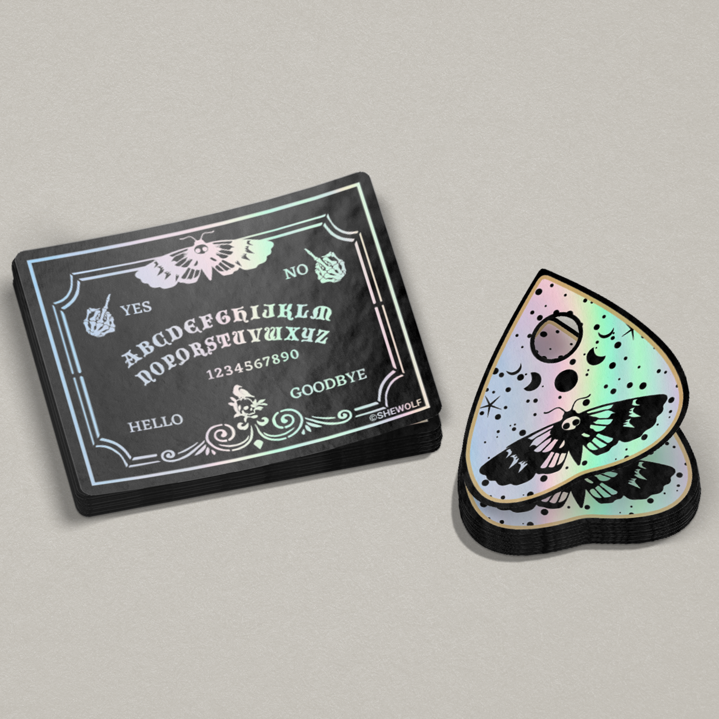 Holographic Ouija board card and moth design sticker on a gray background