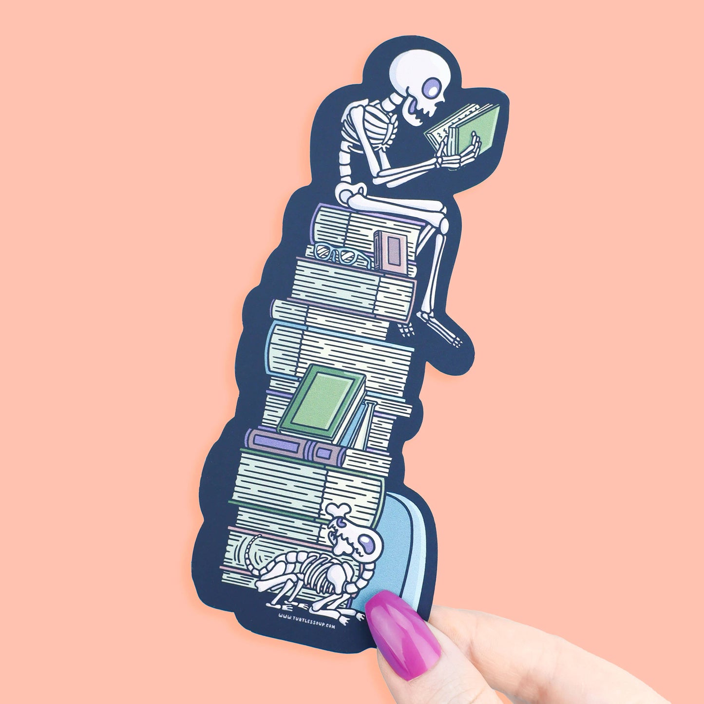 Sticker of a skeleton reading a book on a stack of books with a pink background