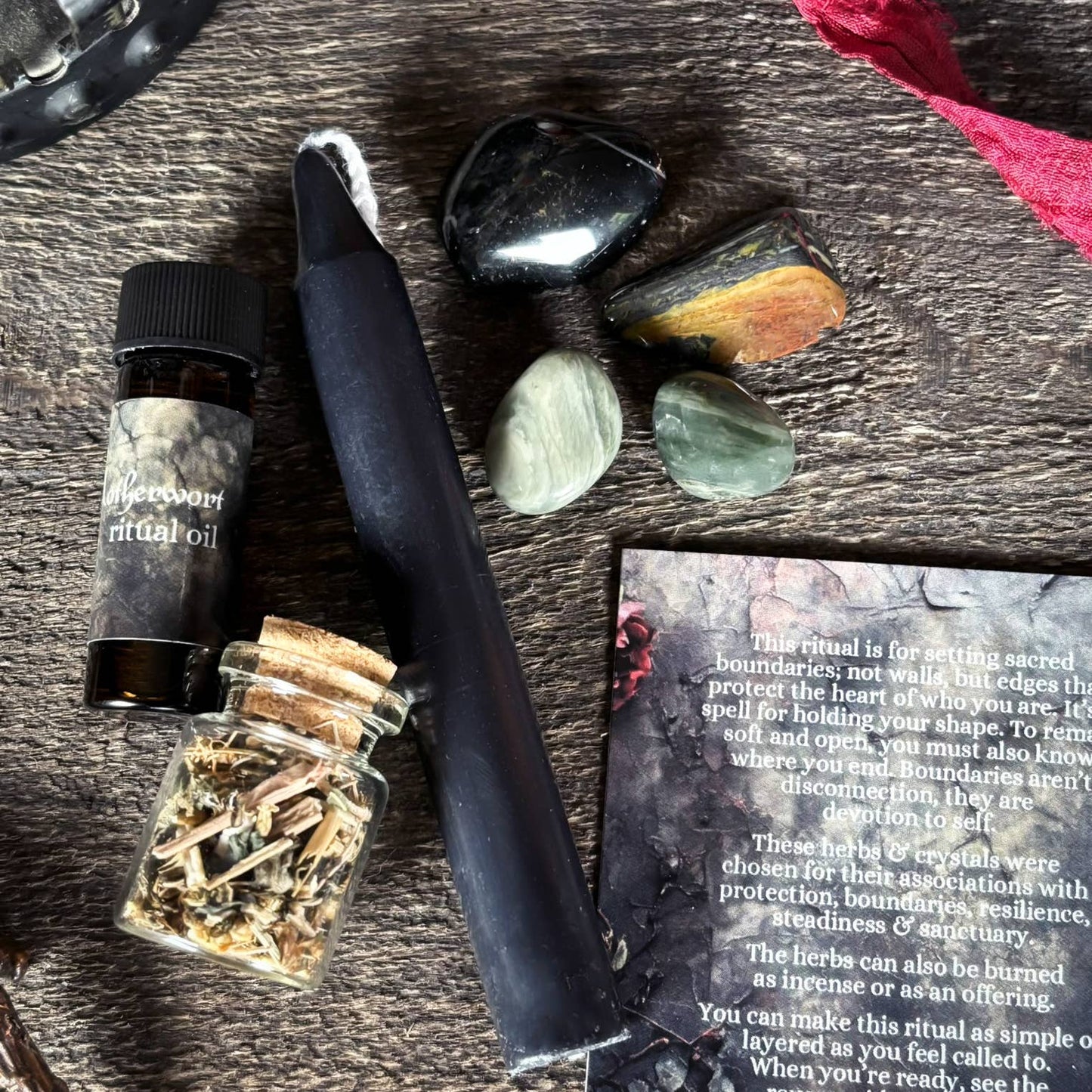Witchcraft supplies including a bottle of oil, herbs, a knife, and stones on a wooden surface.