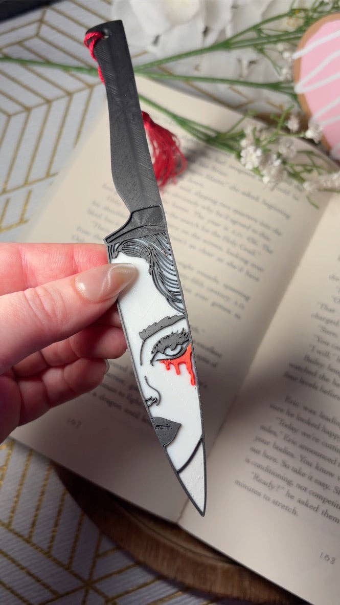 Decorative knife with artistic blade design held over an open book.