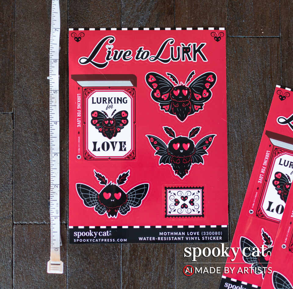 A red sheet of vinyl stickers featuring gothic moth and butterfly designs with hearts, labeled 'Live to LURK' and 'Mothman Love,' shown on a dark wood surface with a ruler for scale and additional sheets partially visible on the right.
