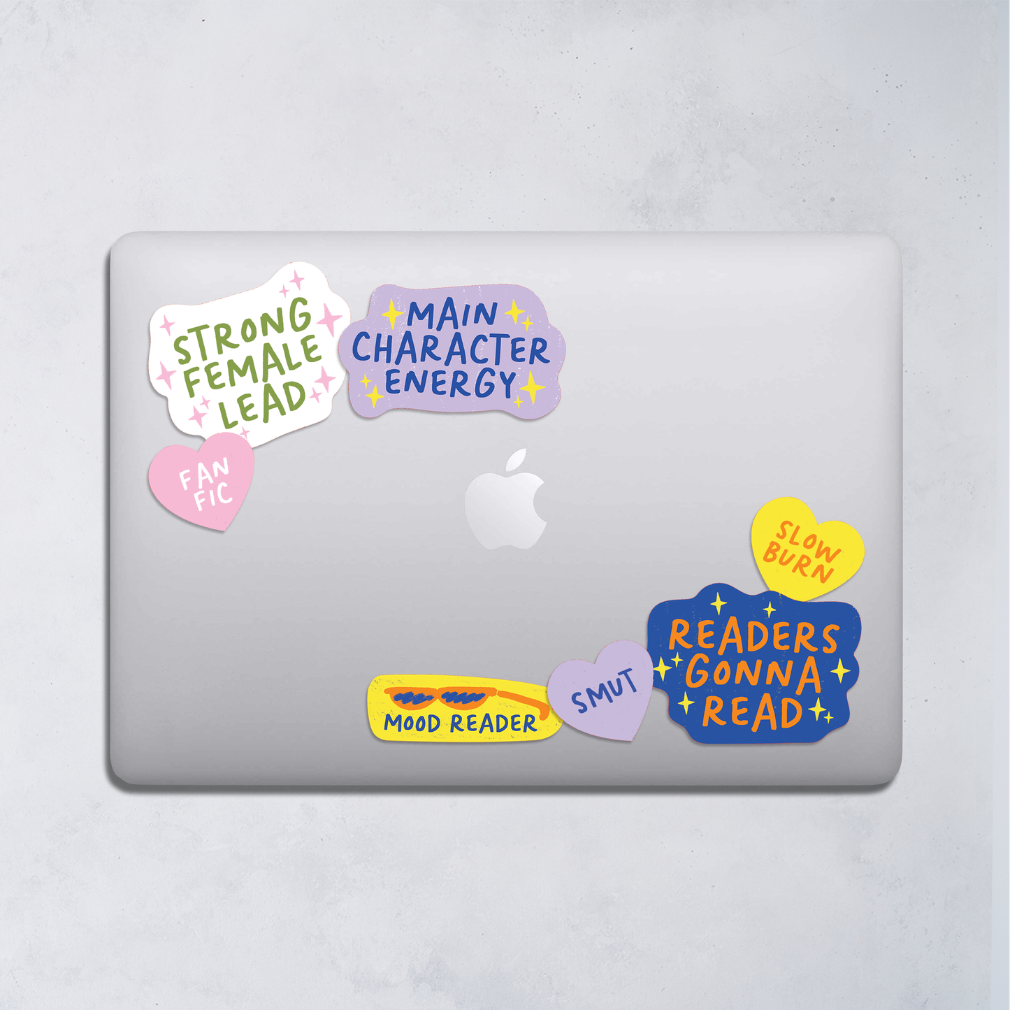 Laptop with colorful book-themed stickers on a light gray background