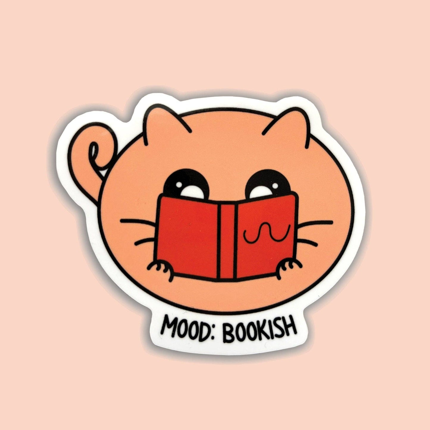 A die-cut sticker featuring a cute peach-colored cartoon cat holding a red book, with the text 'MOOD: BOOKISH' below, shown on a solid pale peach background.