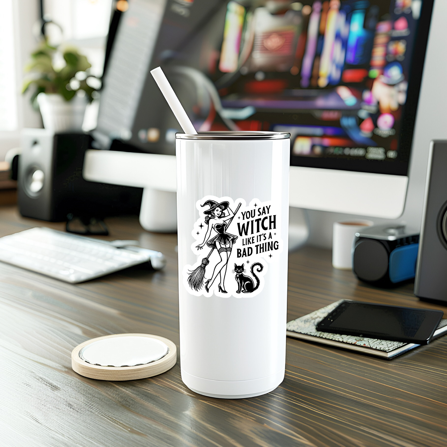 White tumbler with a graphic design on a desk with a computer in the background