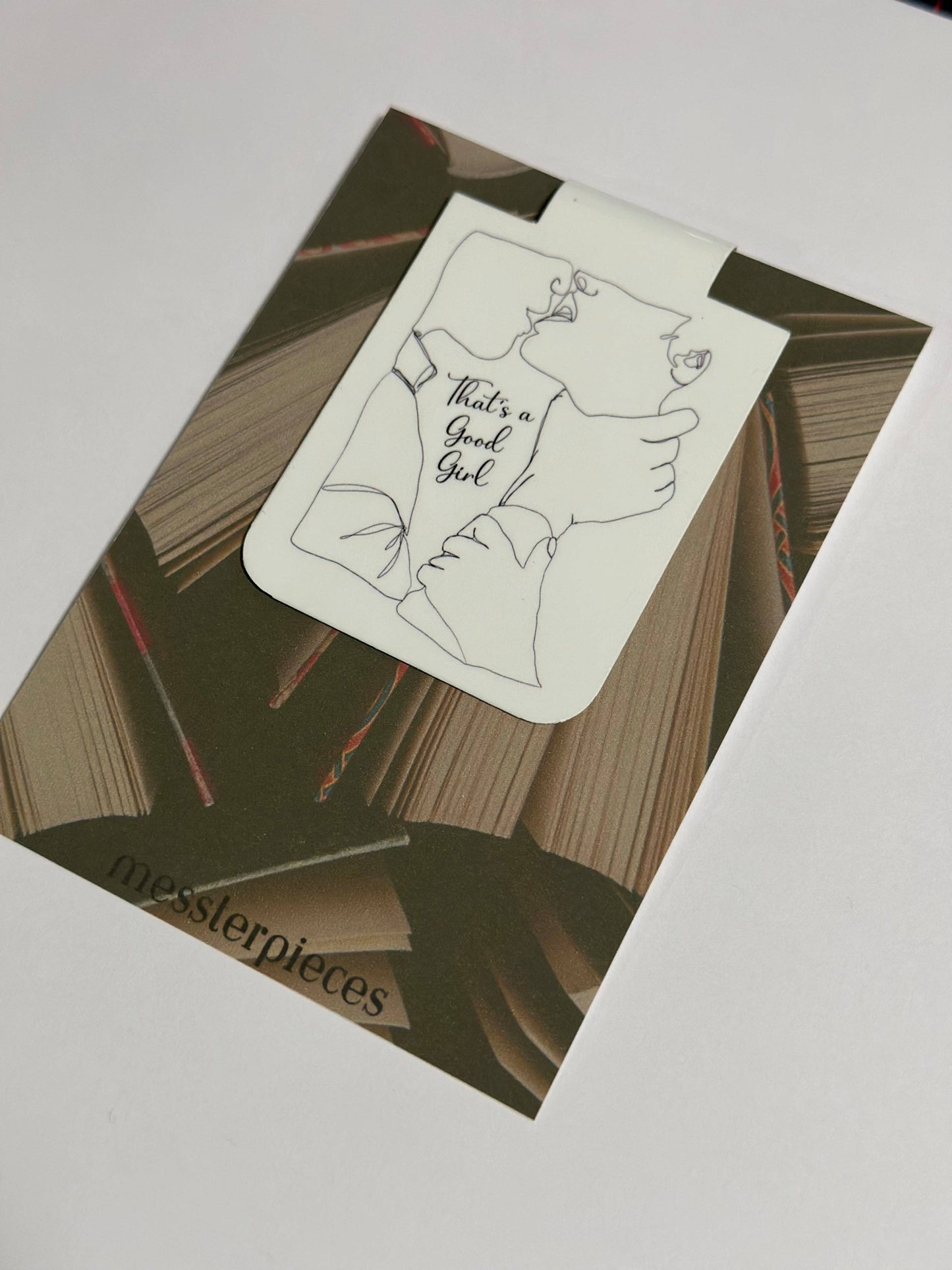 Notebook with a sticker featuring a hand holding a baby outfit with text on a white surface