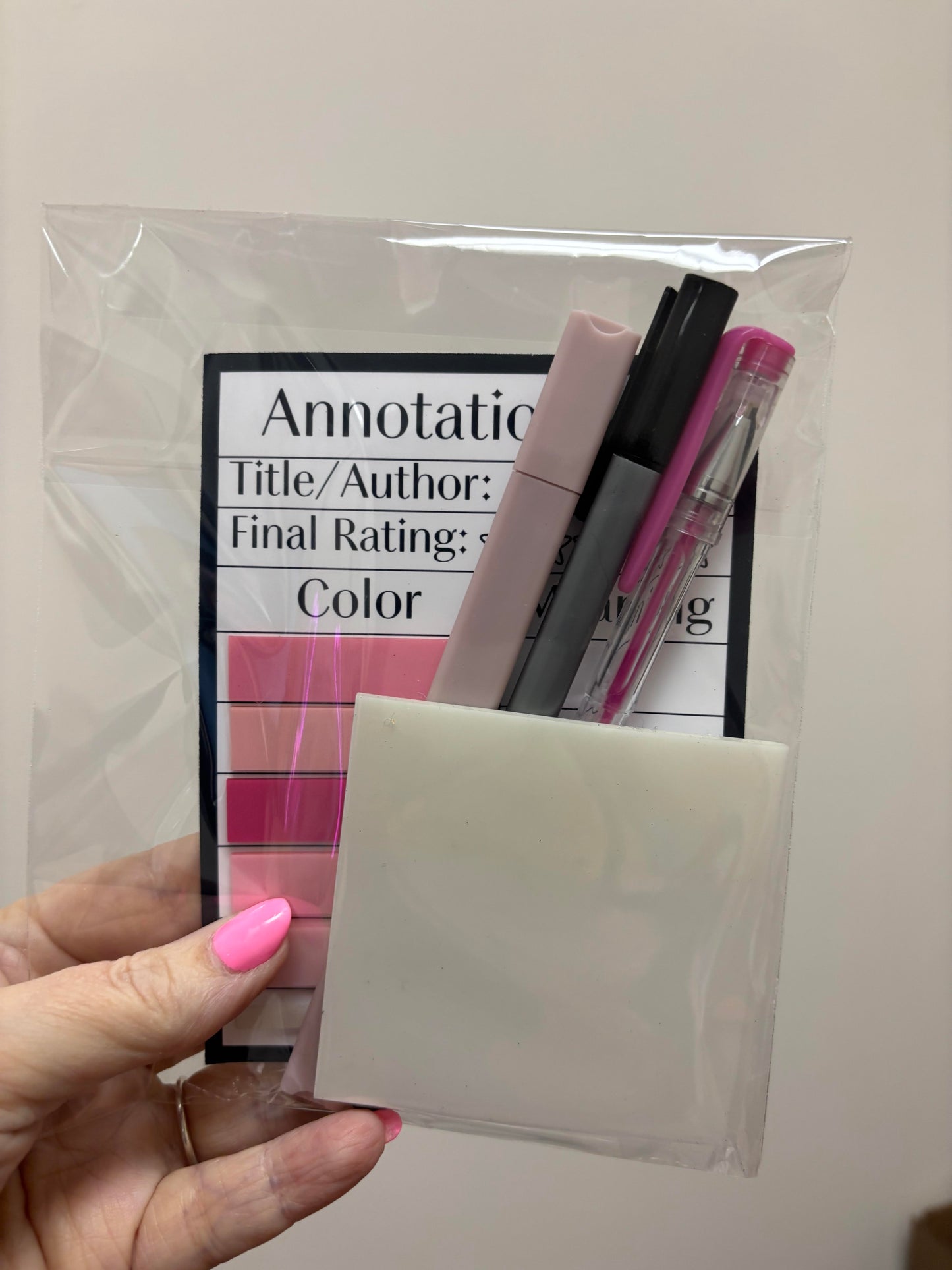 Hand holding a clear plastic bag with stationery items and rating scale.