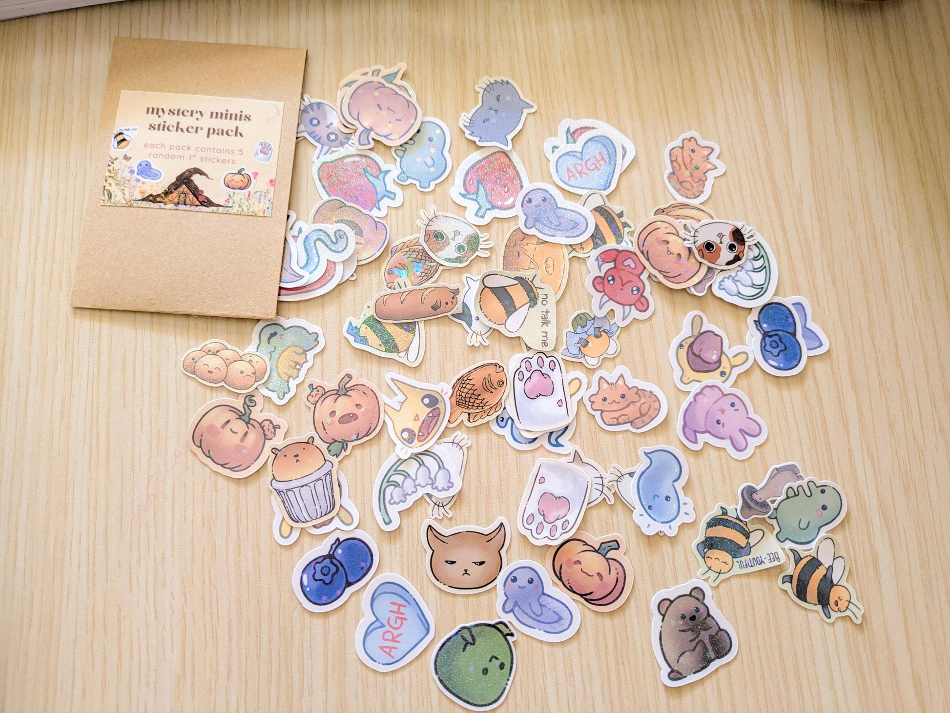 Collection of colorful stickers on a wooden surface with a small box labeled 'mystery mini sticker pack'.