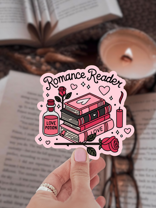 Sticker with 'Romance Reader' design held by a hand, with books and a candle in the background.