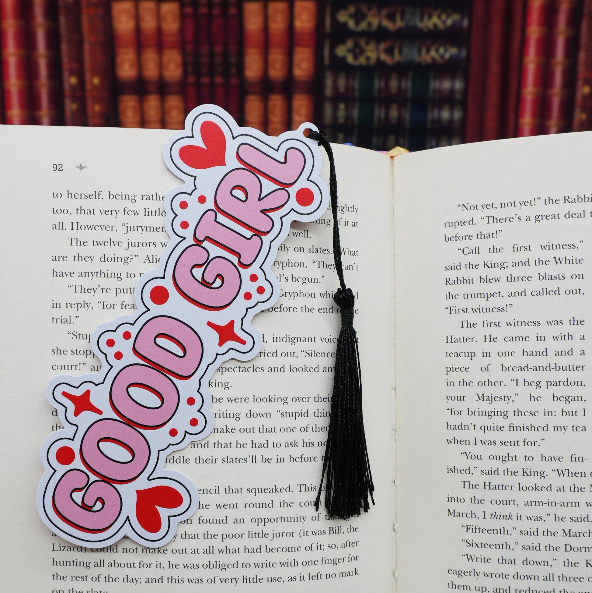 Pink 'Good Girl' bookmark with tassel on an open book