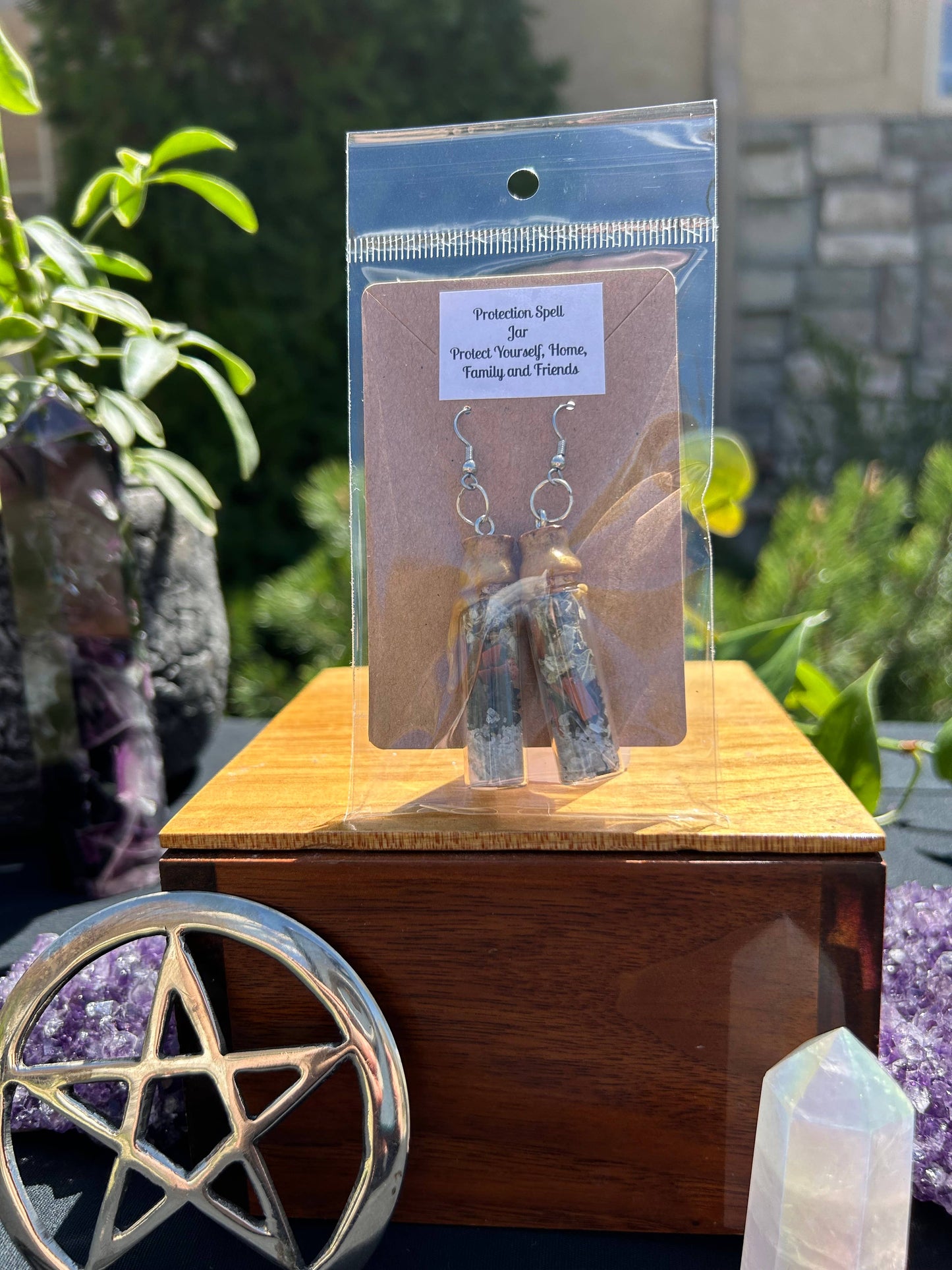 Earring packaging on a wooden stand with crystals and a pentacle symbol in the background