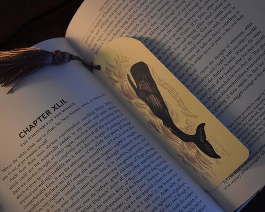 Open book with a whale-themed bookmark on a dark background