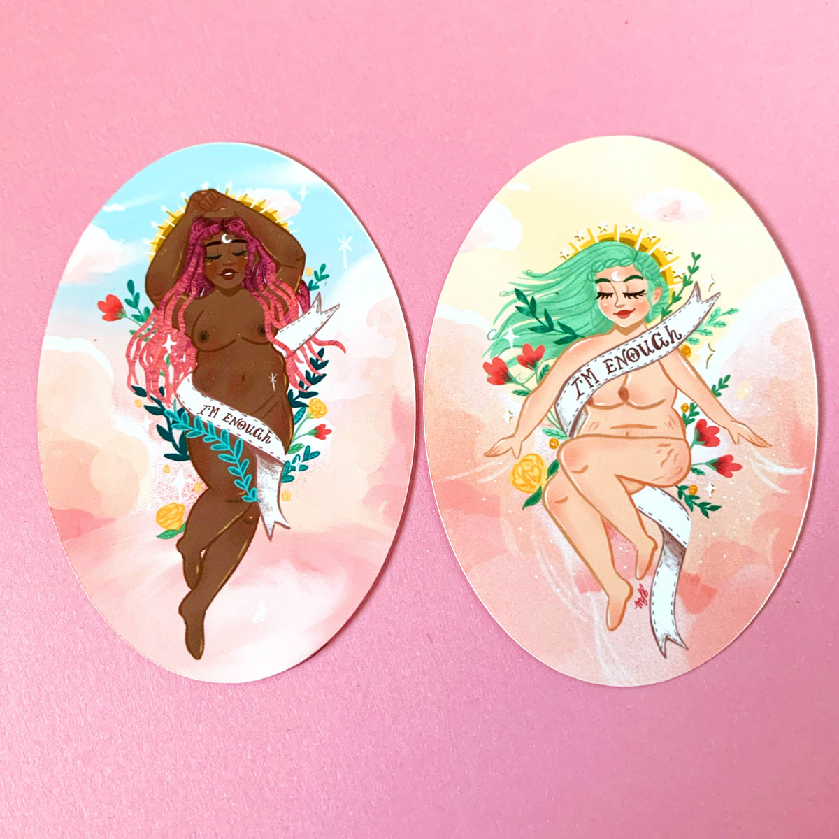 Two oval art prints or stickers displayed side-by-side on a solid pink background. The left print features a dark-skinned woman with pink hair and the text 'I'M ENOUGH'.
