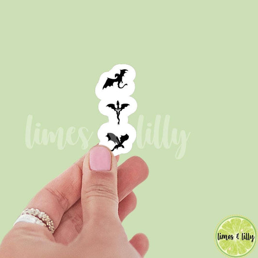Hand holding a stack of small dragon stickers with 'limes & lilly' branding on a light green background.