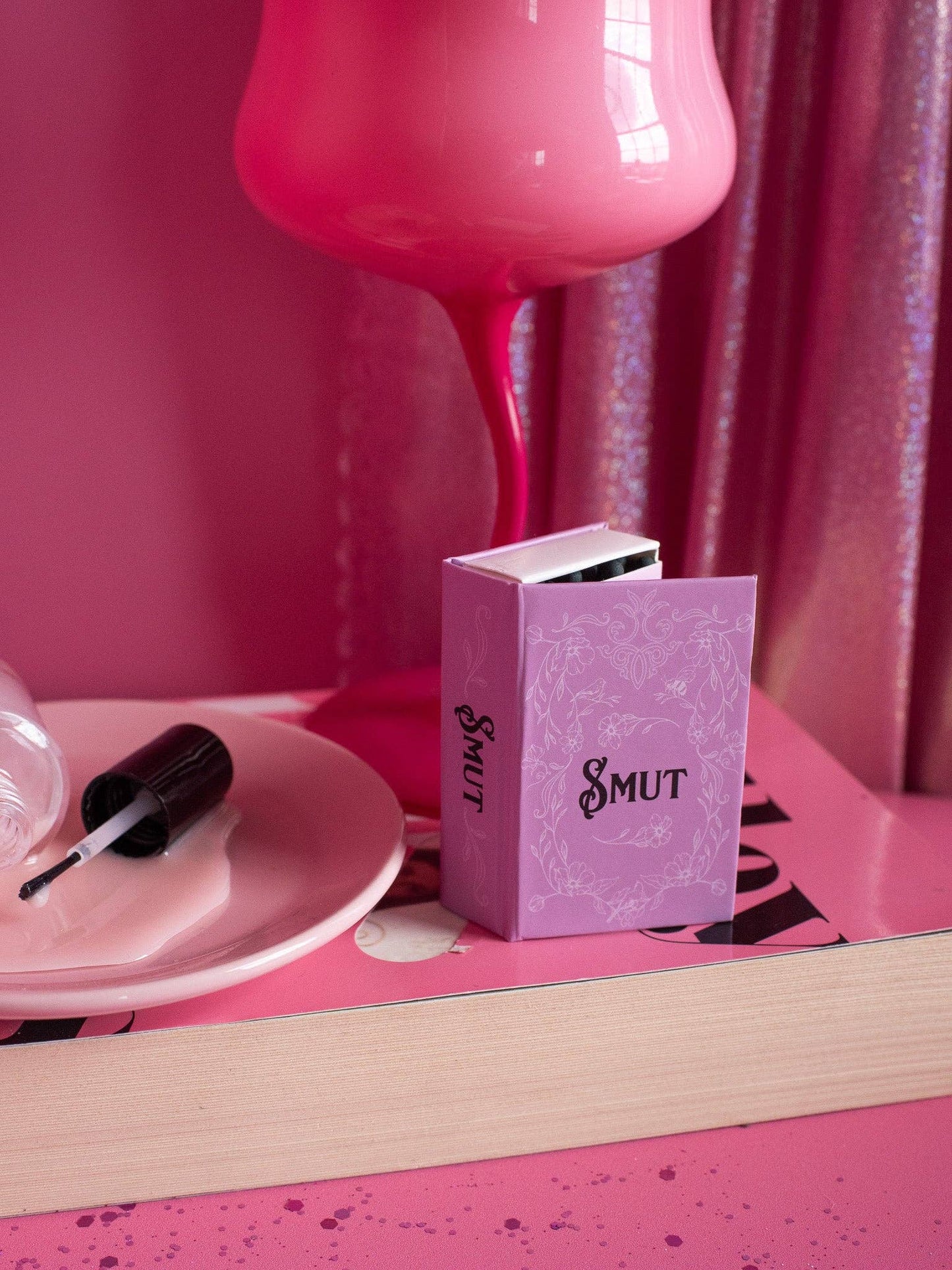 Pink box labeled 'Smut' on a pink surface with a pink lamp in the background