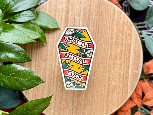 Colorful sticker with text on a wooden surface surrounded by green leaves