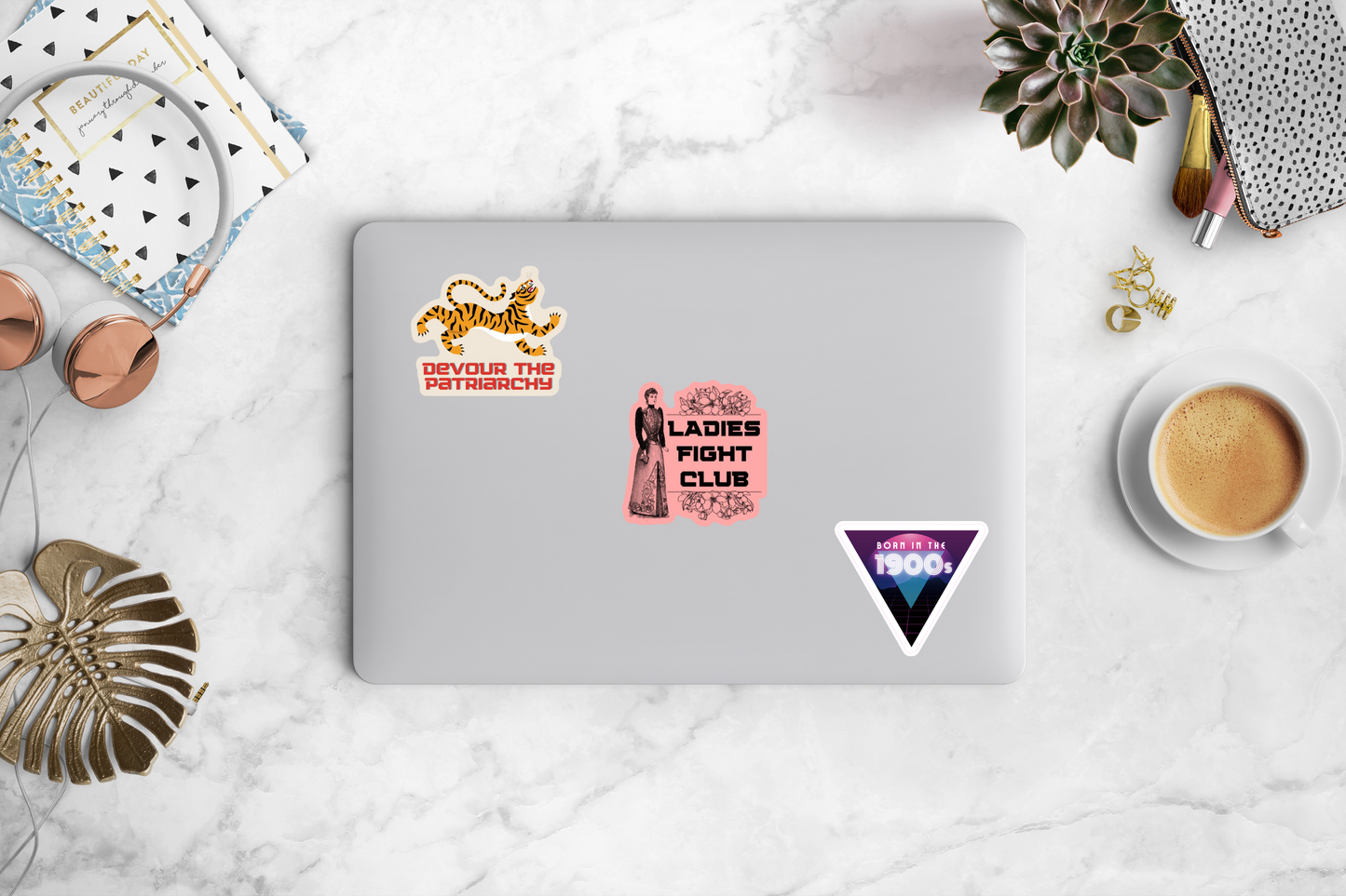 Laptop with stickers on a marble surface with coffee and books