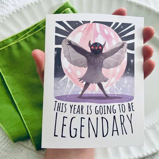 Card with a creature illustration and 'This year is going to be legendary' text, held by a hand.