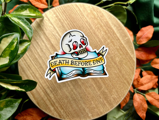 Sticker with 'Death Before Dunk' text on a wooden surface surrounded by leaves