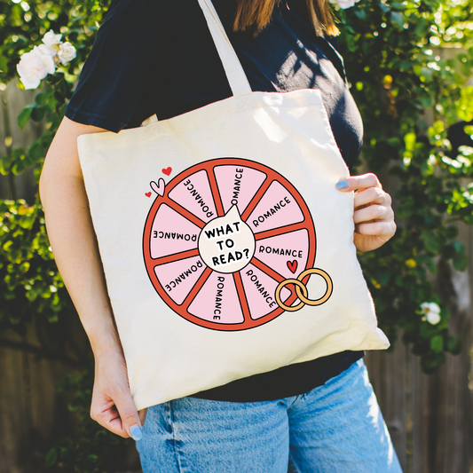 Person holding a tote bag with 'What to Read?' design against a natural background