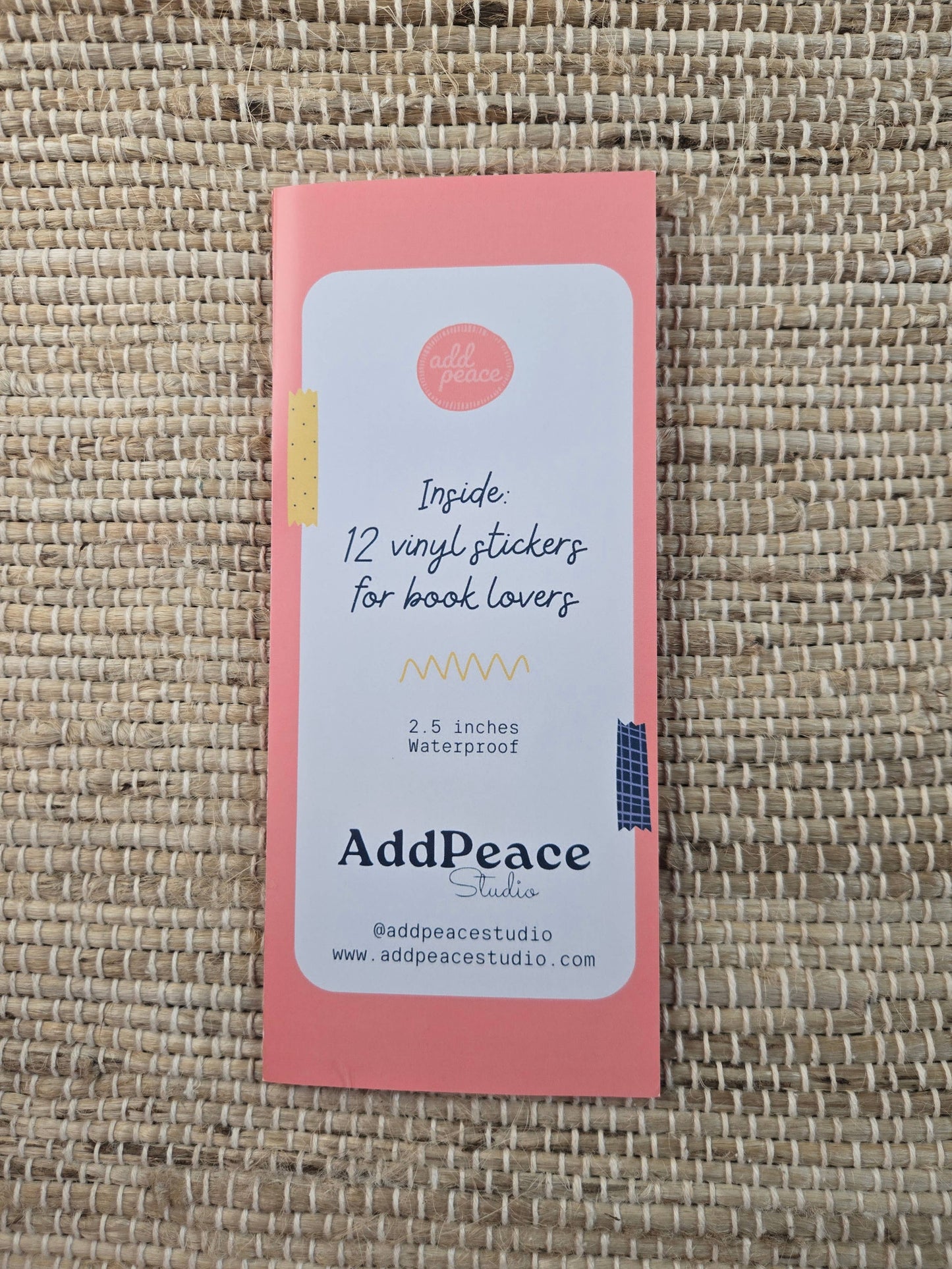 Pink packaging with AddPeace branding on a woven surface