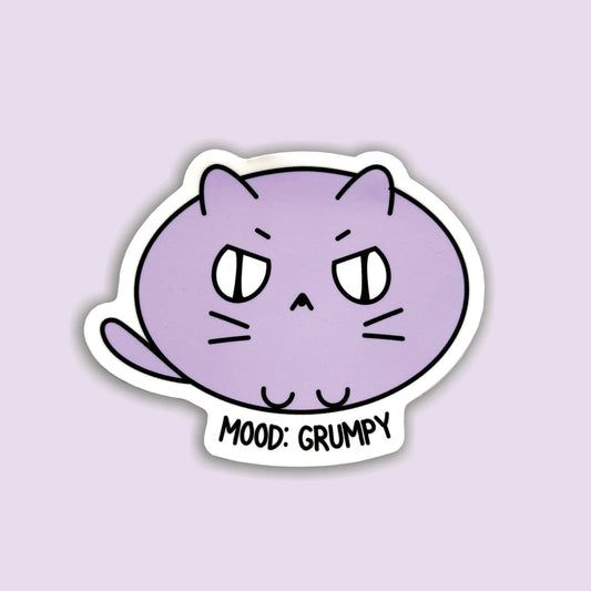 A die-cut sticker featuring a cartoon purple cat with a grumpy expression and the text 'MOOD: GRUMPY' on a light lavender background.