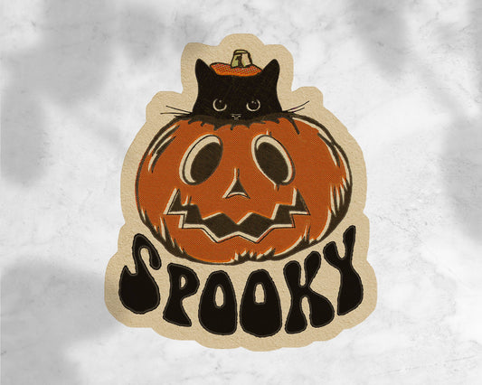 Halloween-themed sticker with a black cat on a pumpkin and 'Spooky' text on a textured white background