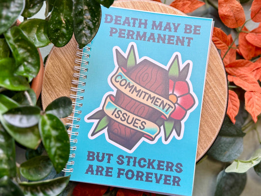 Notebook with a sticker on it, surrounded by plants