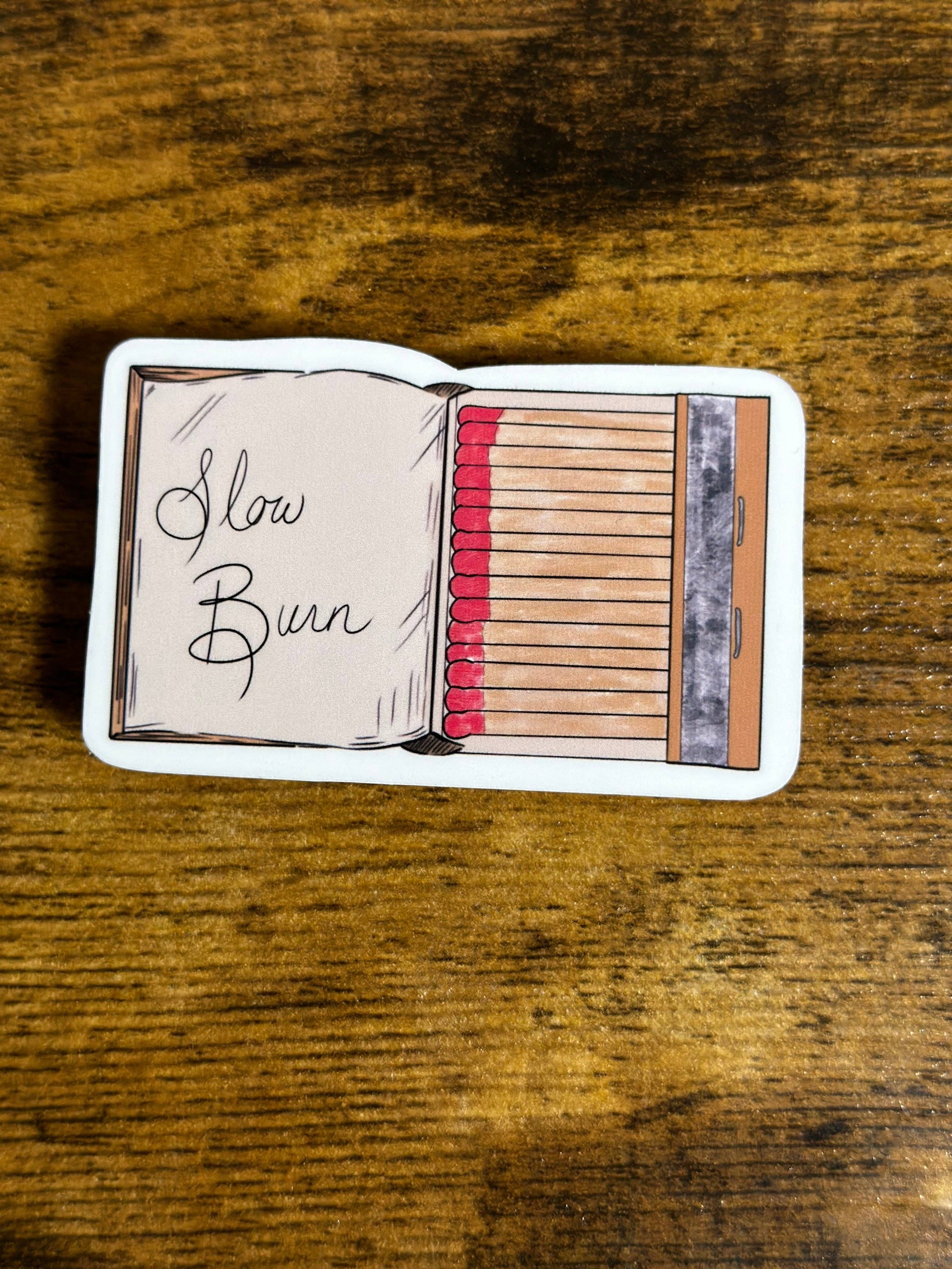 Matchbook with 'Slow Burn' text on a wooden surface