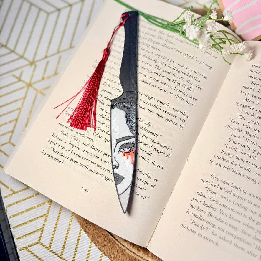 Decorative bookmark with a face design on an open book