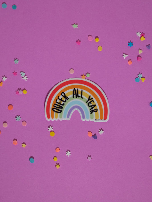 Rainbow sticker with 'Queer All Year' text on a purple background with confetti