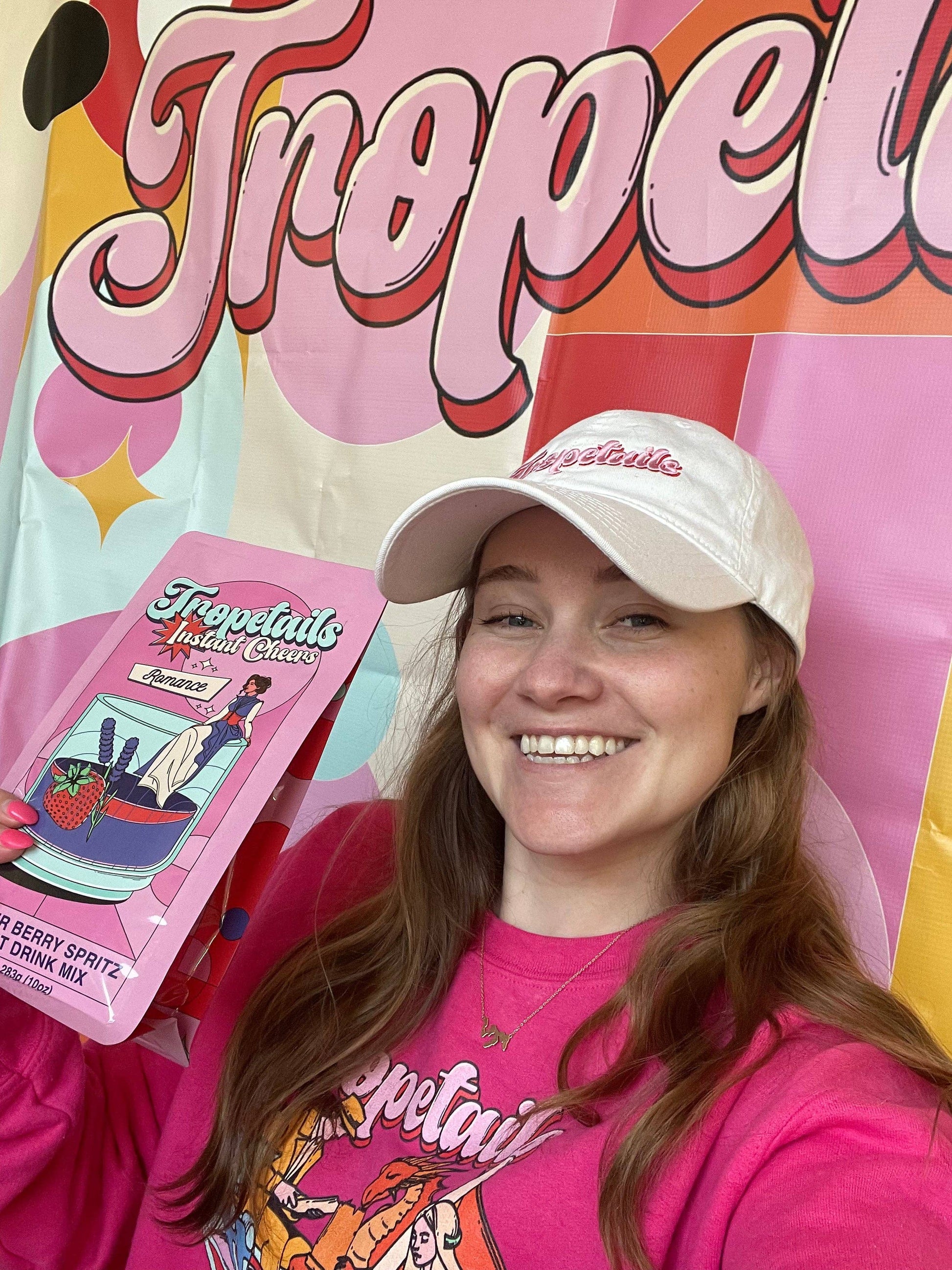 Person wearing a 'Tropelait' branded hat and shirt, holding a product package with colorful text and graphics.