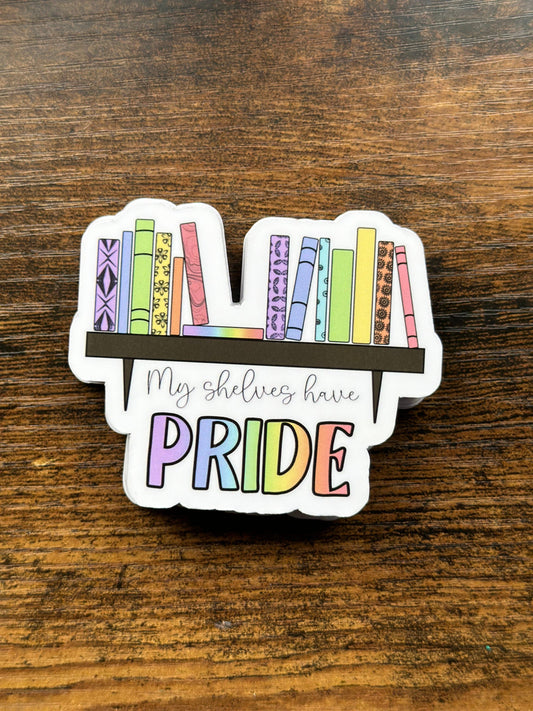 Sticker with rainbow books and 'My shelves have PRIDE' text on a wooden surface