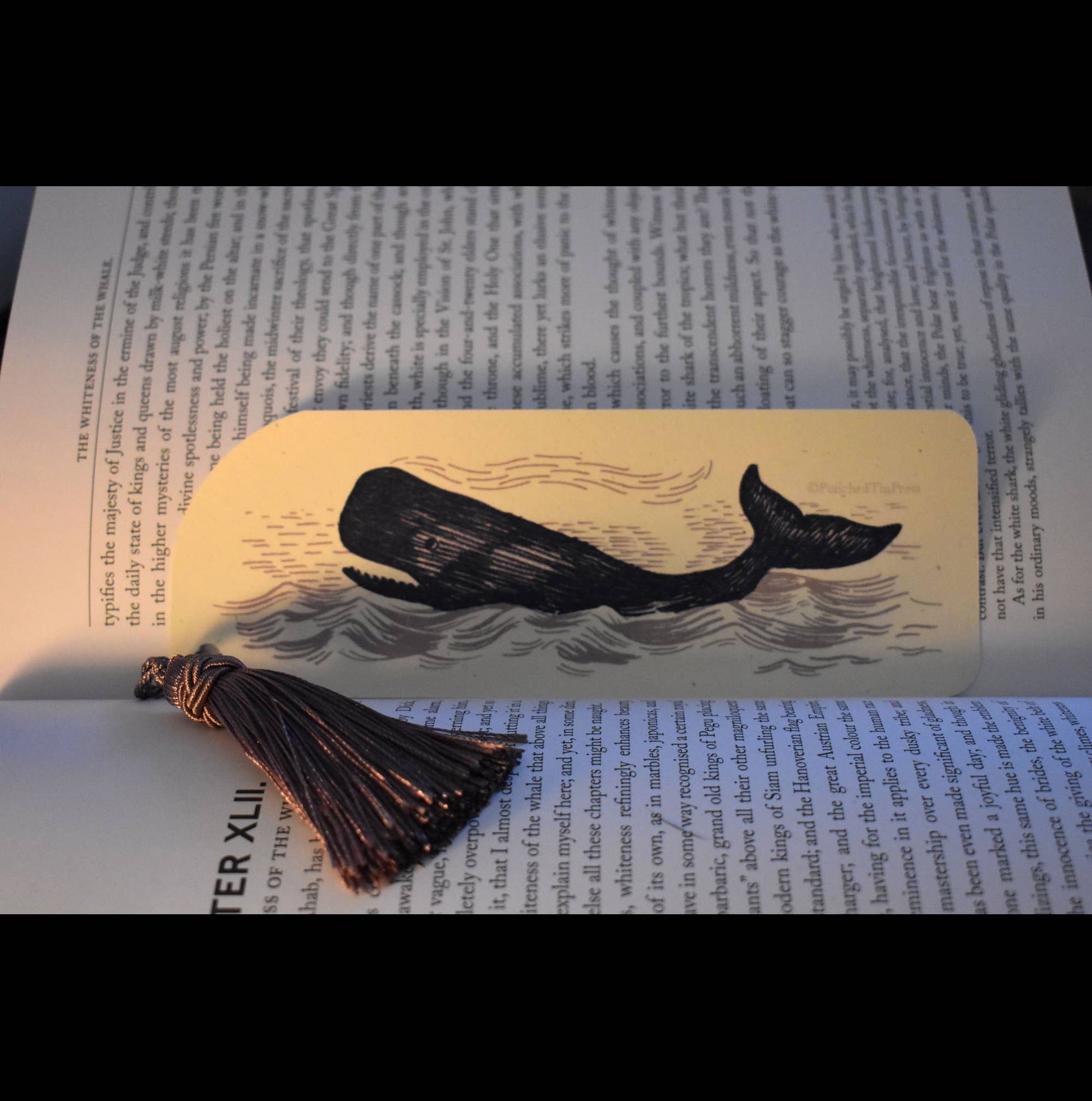 Whale-themed bookmark with tassel on an open book