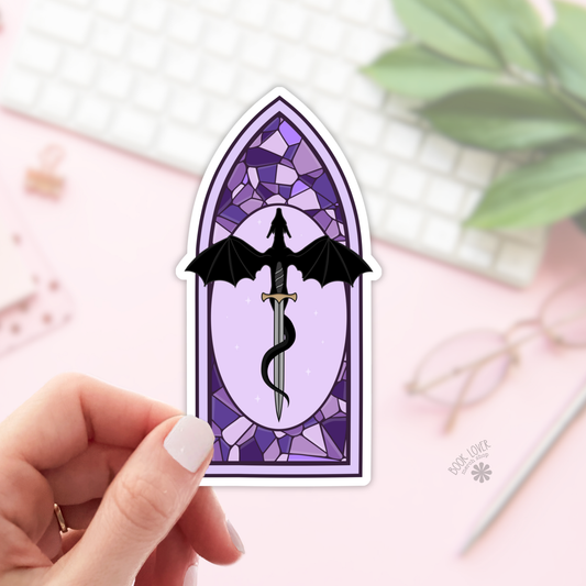 Sticker of a dragon and sword design in a stained glass window style held by a hand.