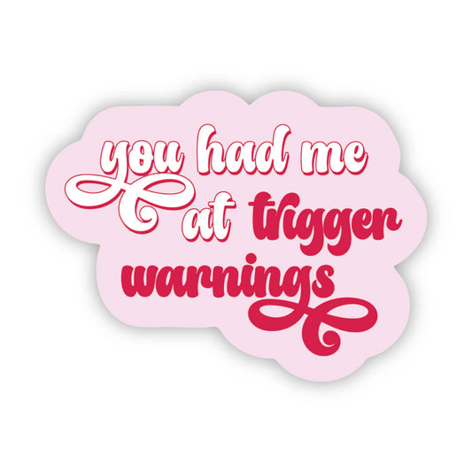 Pink cloud-shaped sign with red text 'you had me at trigger warnings' on a white background