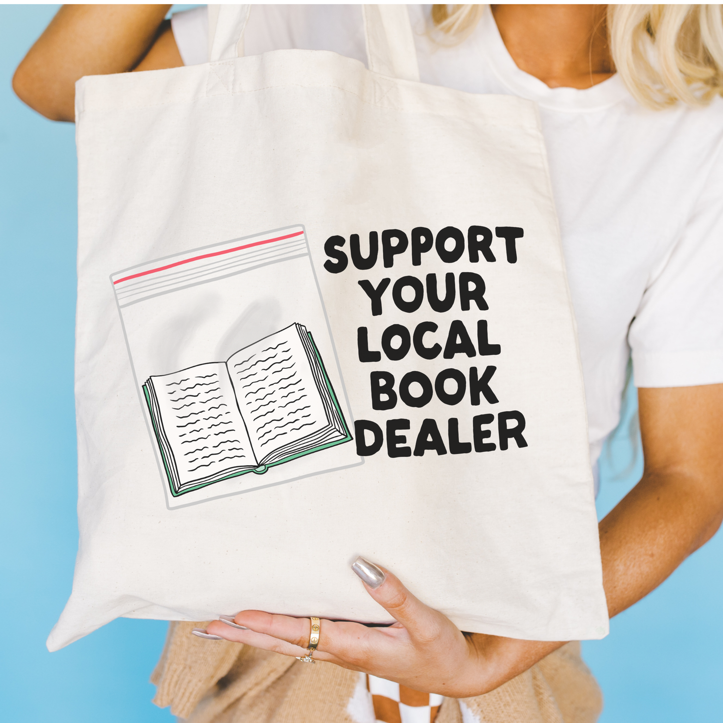 Person holding a tote bag with 'Support Your Local Book Dealer' text and a book illustration.