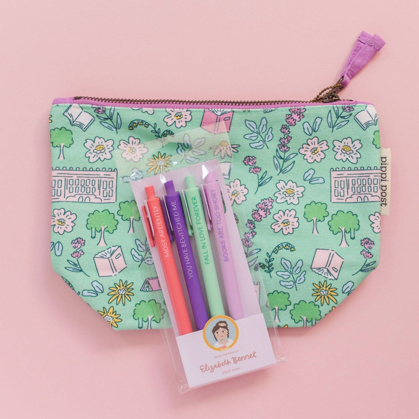 Floral-patterned pouch with pens and packaging on a pink background