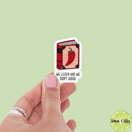 Hand holding a sticker with a book and chili pepper design on a light green background