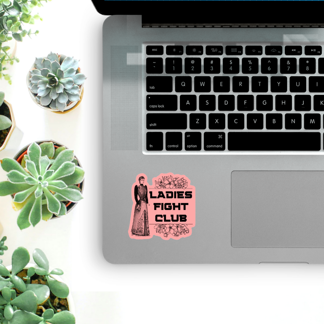 Laptop with 'Ladies Fight Club' sticker on a white surface with succulents