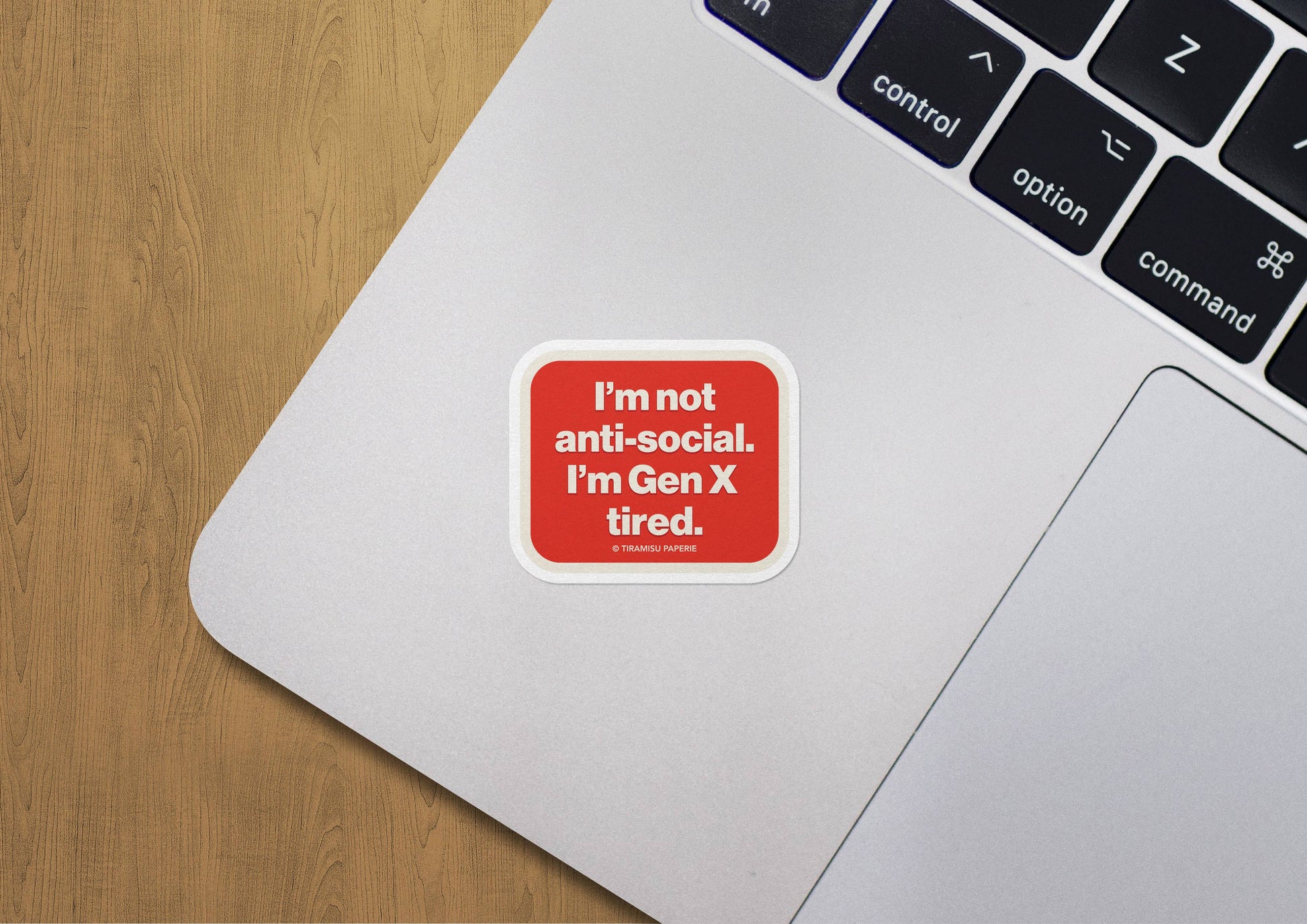 Laptop with a sticker on the palm rest area, featuring text 'I'm not anti-social. I'm Gen X tired.'