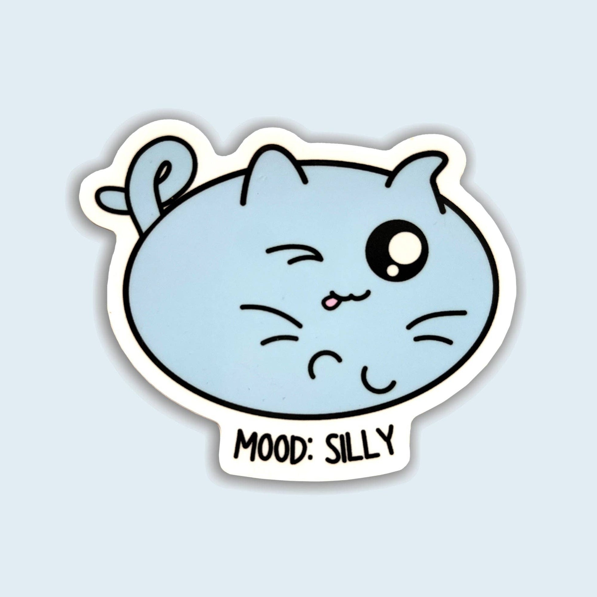 A die-cut sticker featuring a light blue cartoon cat face with one winking eye and the text 'MOOD: SILLY' below, shown on a pale blue background.