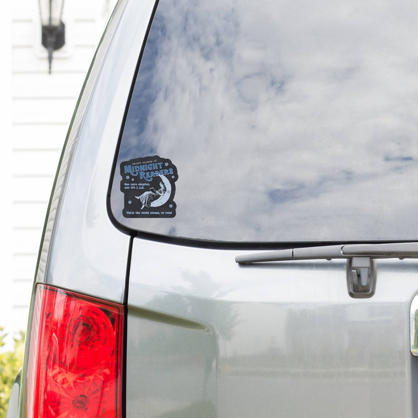 Car with a sticker on the rear window, featuring text and graphics.