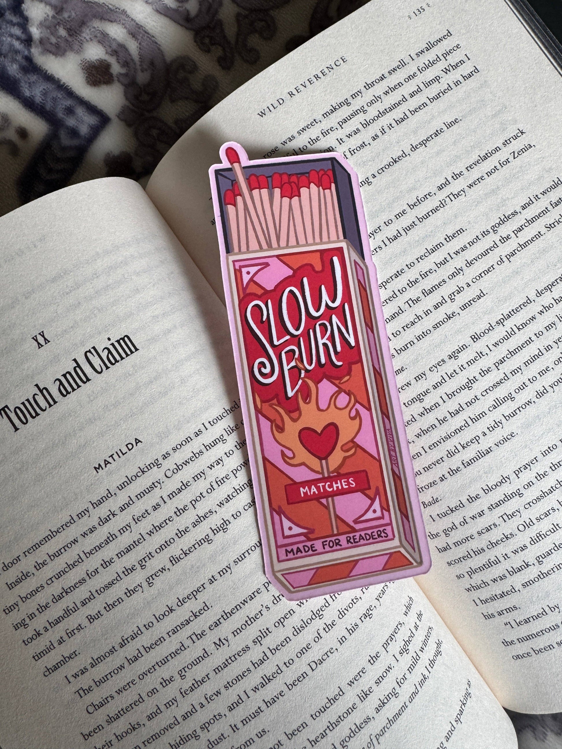 Bookmark with 'Slow Burn Matches' design on an open book