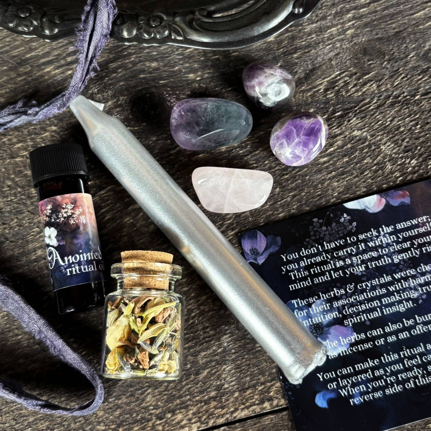 Herbal jar, candle, and crystals on a wooden surface with a ritual book.