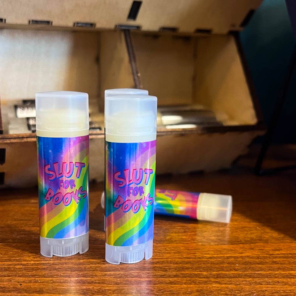 Two lip balm tubes with colorful labels on a wooden surface.