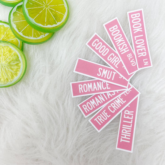 Pink book-themed stickers on a white surface with lime slices.