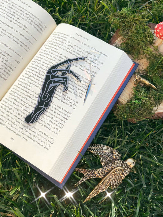 A skeletal hand bookmark on an open book with a natural background