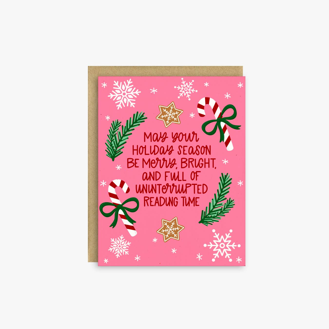 A pink Christmas greeting card with a kraft envelope, featuring holiday illustrations like snowflakes, candy canes, pine branches, bows, and gold stars, with the text 'Merry your holiday season be merry bright, and full of uninterrupted reading time.'.
