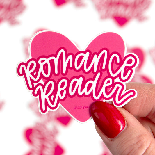 Sticker with 'Romance Reader' text held by a hand with red nail polish against a heart-patterned background.