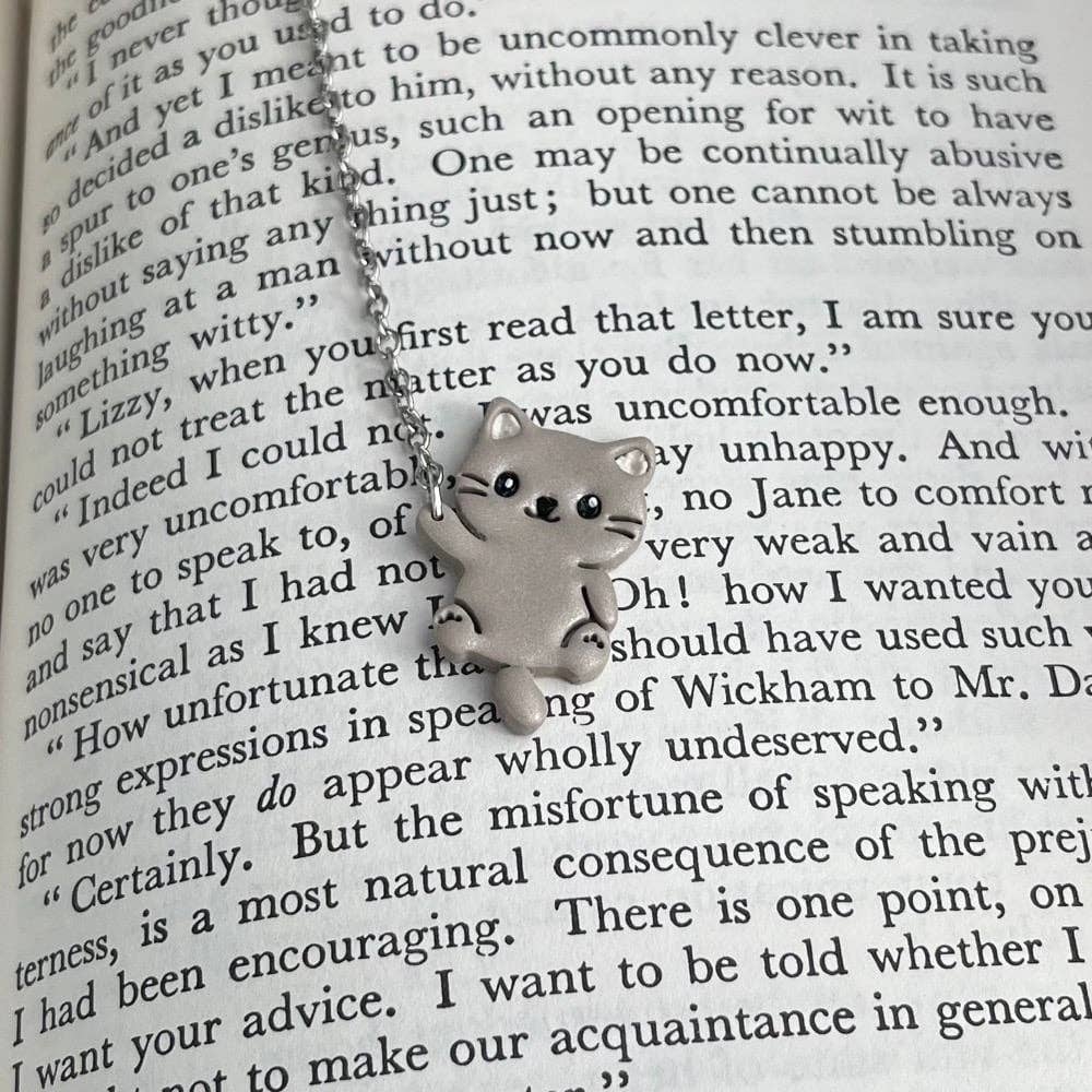 Cat-shaped bookmark on a chain over an open book